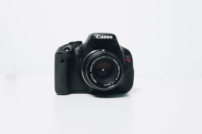 A camera and a few accessories laid out on a wooden table.